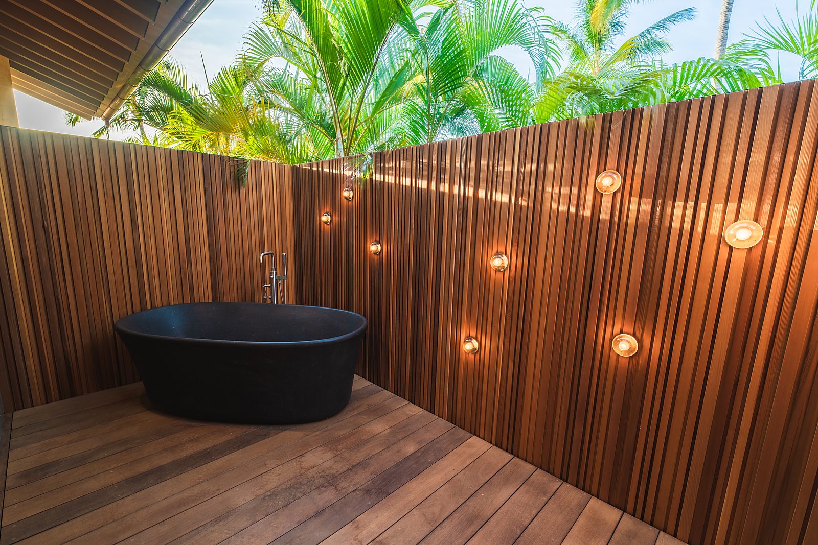 Black stone outdoor bath against a cedar slat wall